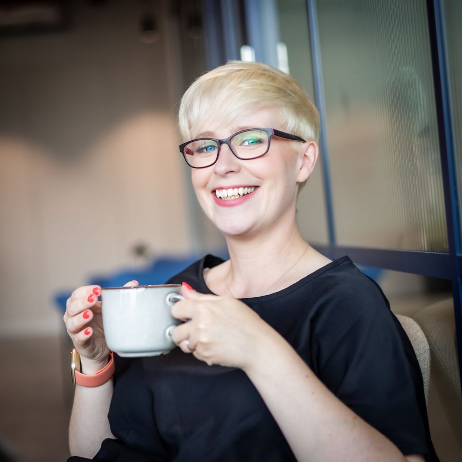Jenny smiling and holding a cup of tea